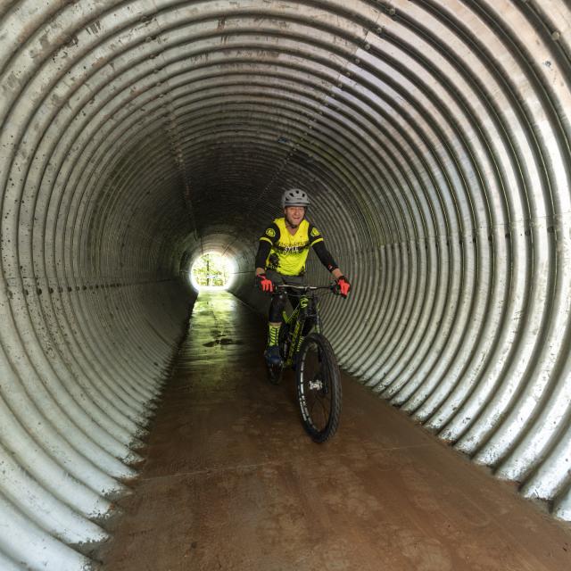 Mountain Biker rides through a tunnel the Monument Trails at Hobbs State Park