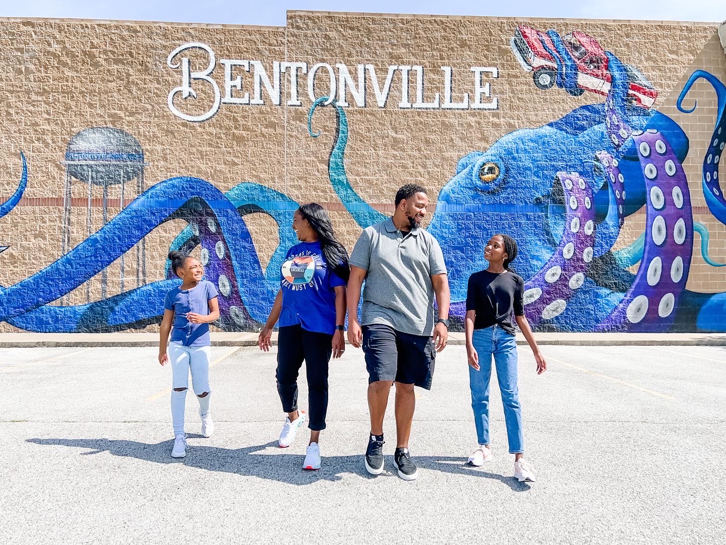 A family of four laughing in front of a mural of an Octopus 