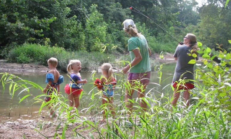 Parents fishing and kids swimming