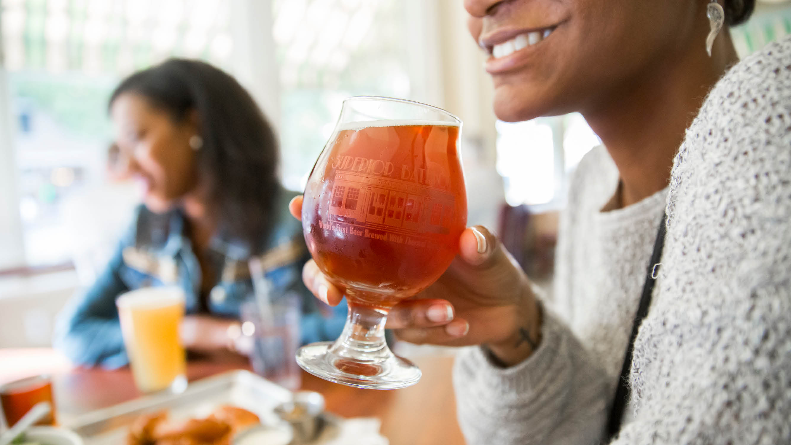 A woman drinking a beer at the Superior Bathhouse Brewery