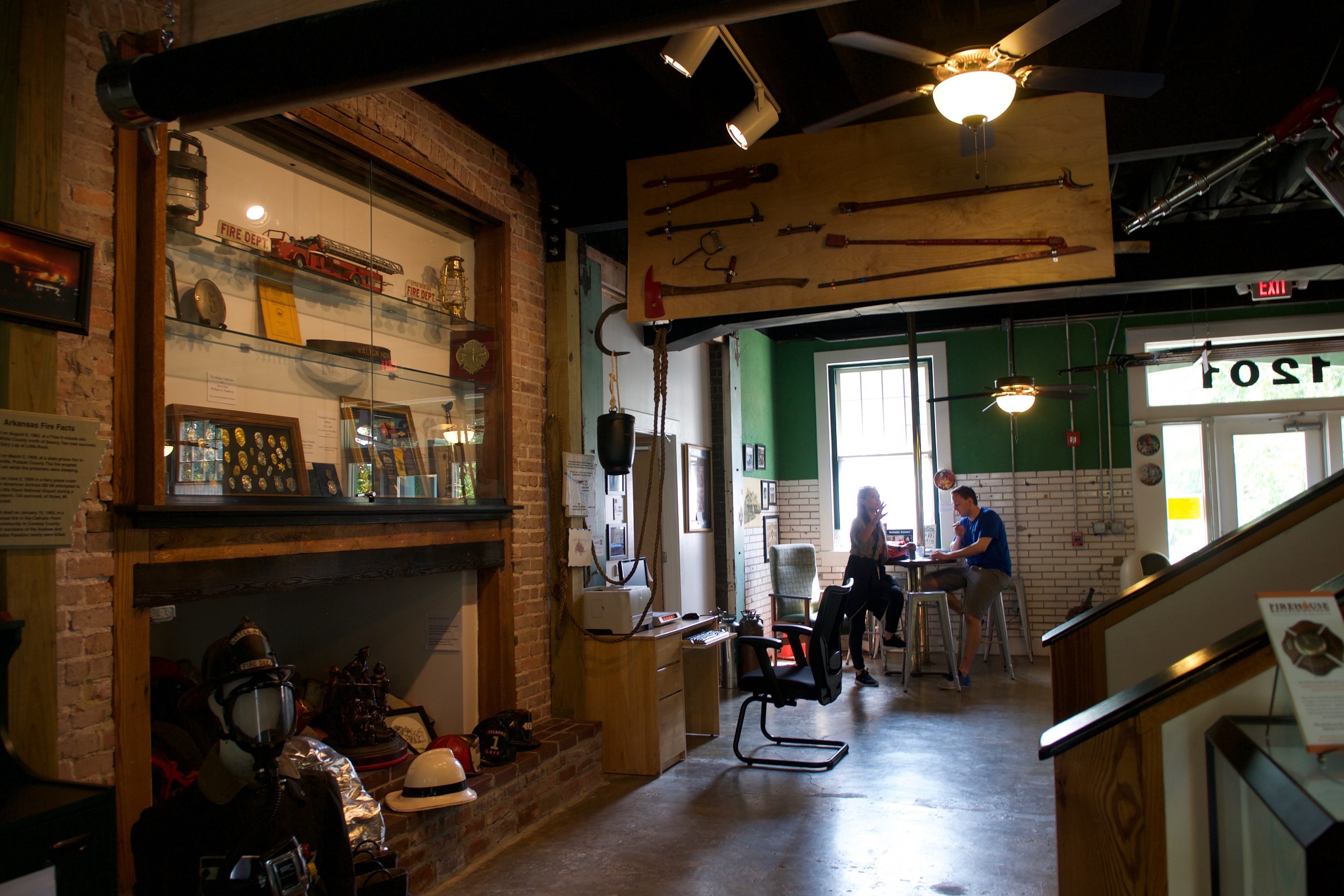 Couple chatting at a table inside the Firehouse Museum and Hostel surrounded by memorabilia. 