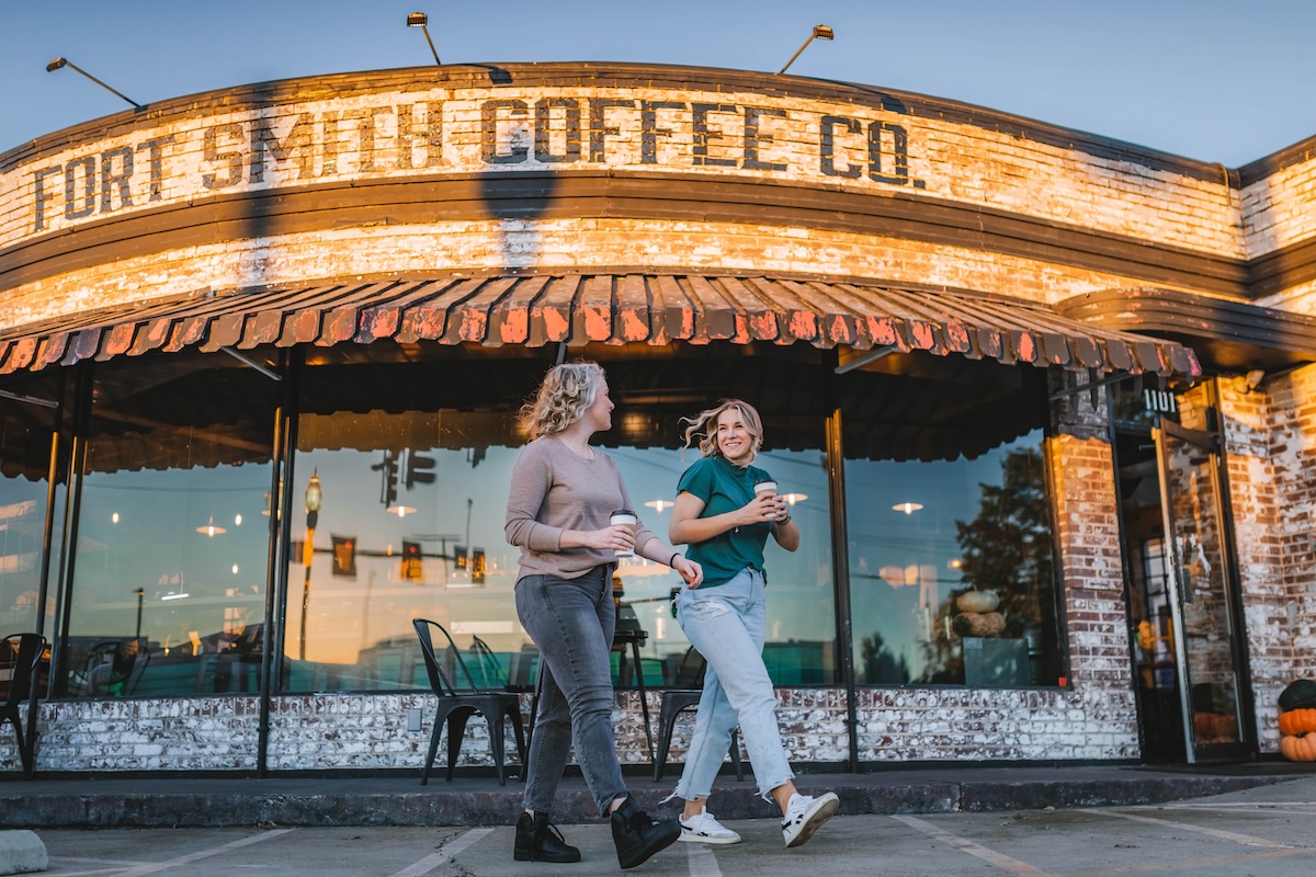 women smiling and walking with coffee