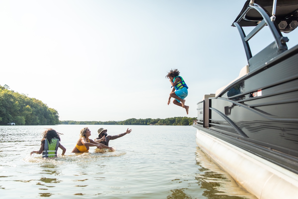 family swimming in lake hamilton and jumping in water off the boat