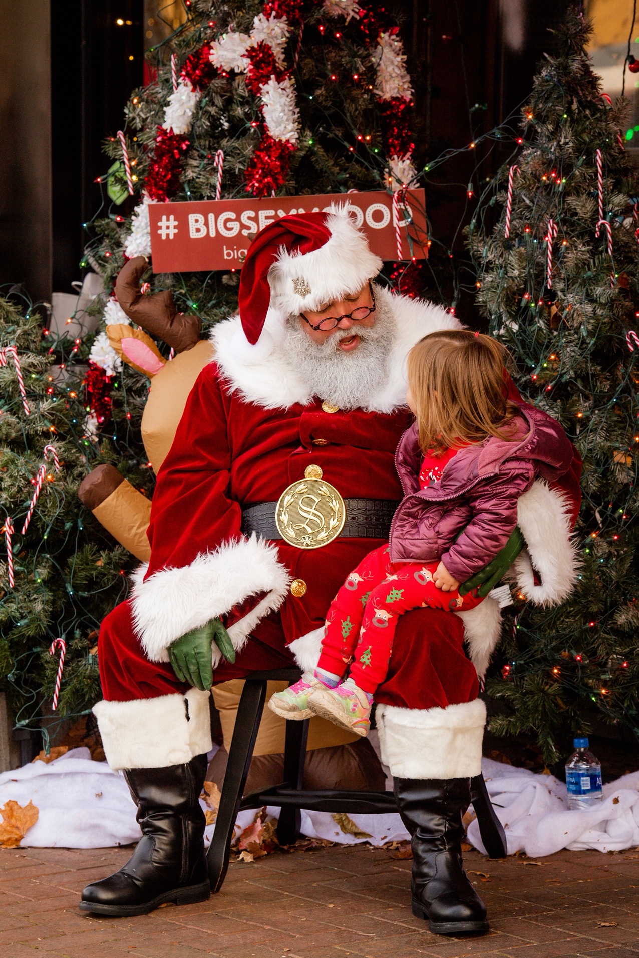 A young girl sits on Santa's lap, telling him what she wants for Christmas in downtown Springdale, AR.