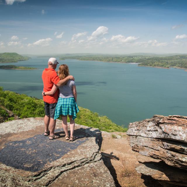 Two hikers embrace as they look at the view of Greers Ferry Lake from the top of Sugar Loaf Mountain