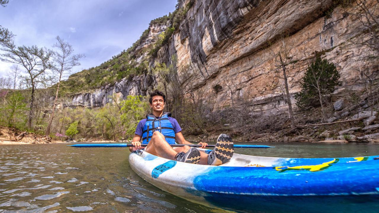 Kayaker on the Buffalo National River with the bluffs overhead
