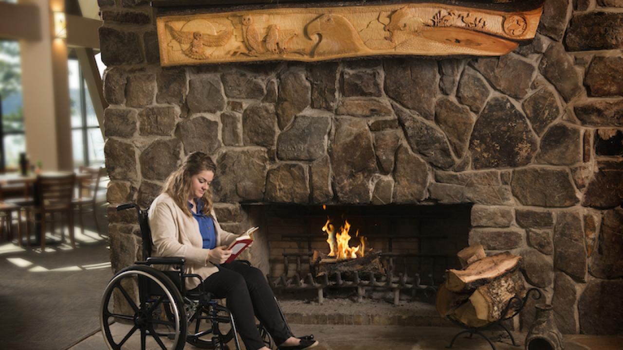 Woman in wheelchair in front of a fireplace ad Degray Lake