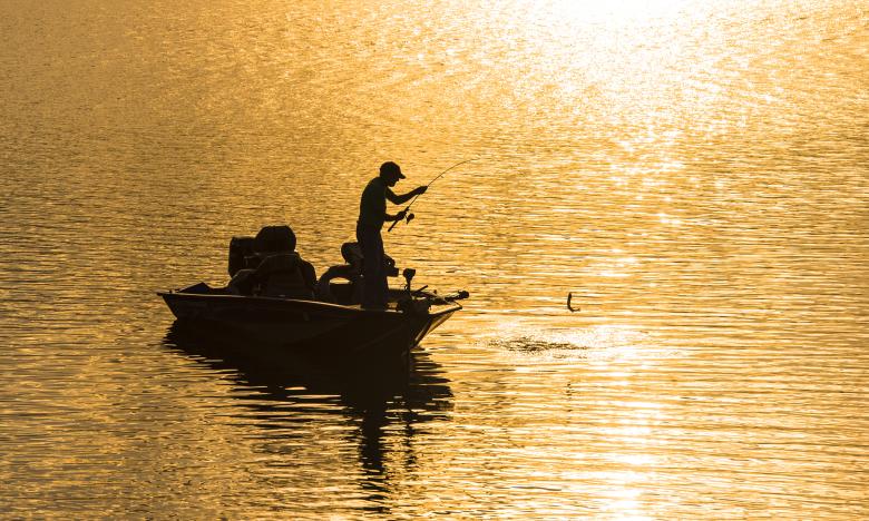 Fisherman casts his reel at sunrise off Lake Ouachita