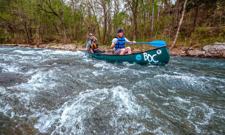 Kayakers head over the rushing white waters of the Buffalo National River
