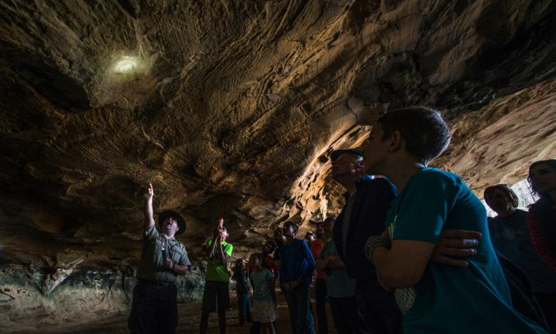 Park visitors being show historical Native American markings by a park ranger at the Rock House Cave at Petit Jean State Park in Morrilton 