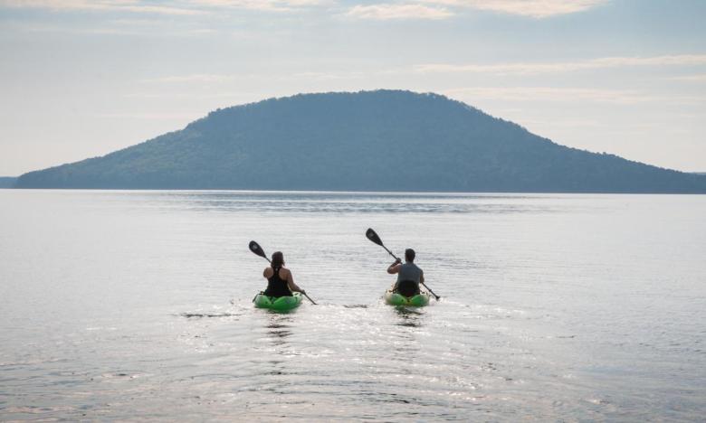A couple kayaks on Greers Ferry Lake with Sugar Loaf Mountain in the distance