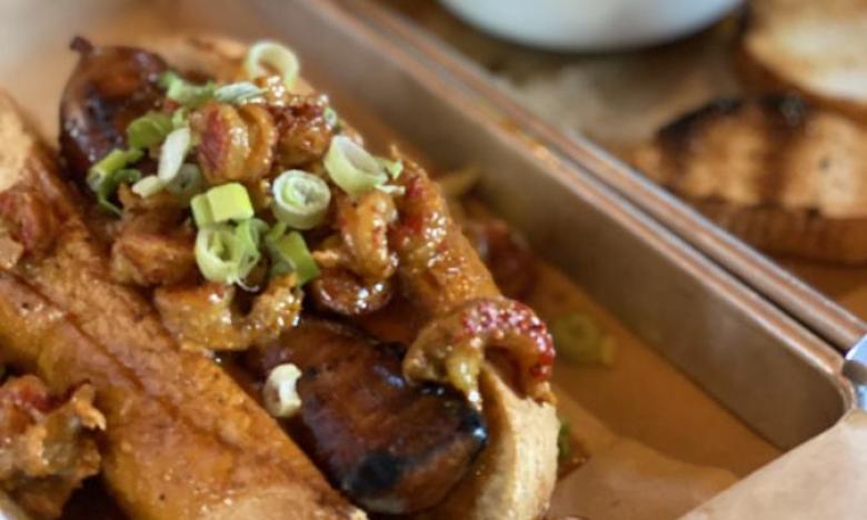 (Above) Cajun Chili Dog with smoked gator, pork sausage and crawfish cream sauce on a hoagie roll. (Below) Shrimp and Grit Stackers with smoked cheddar grit cakes, sauteed shrimp, Andouille sausage and spicy Cajun sauce.