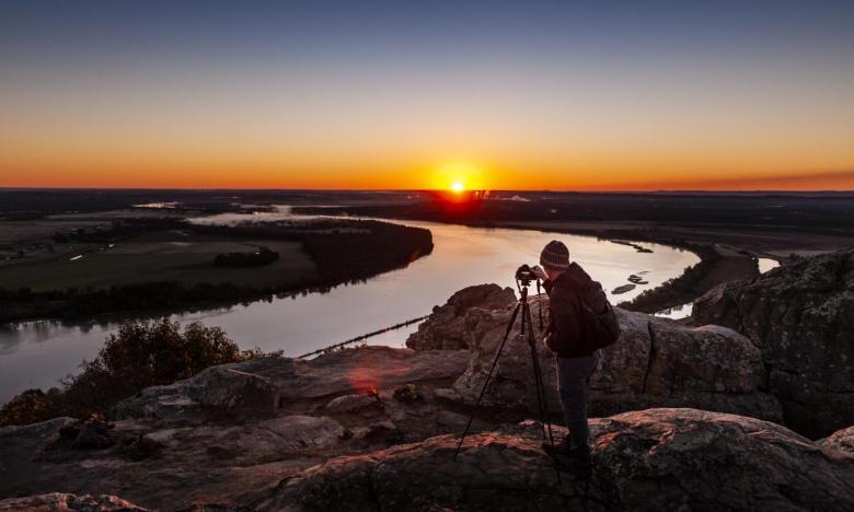 A photographer takes a sunrise photo at Stouts Point at Petit Jean State Park.