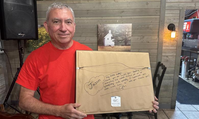 Jason Hutcheson holding up a signed photo from Taylor Swift