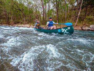 Kayakers head over the rushing white waters of the Buffalo National River
