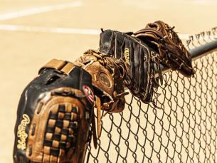 Baseball mitts lined along a fence