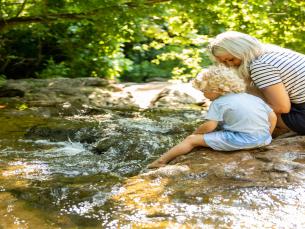 A mother an child sitting along a creek 