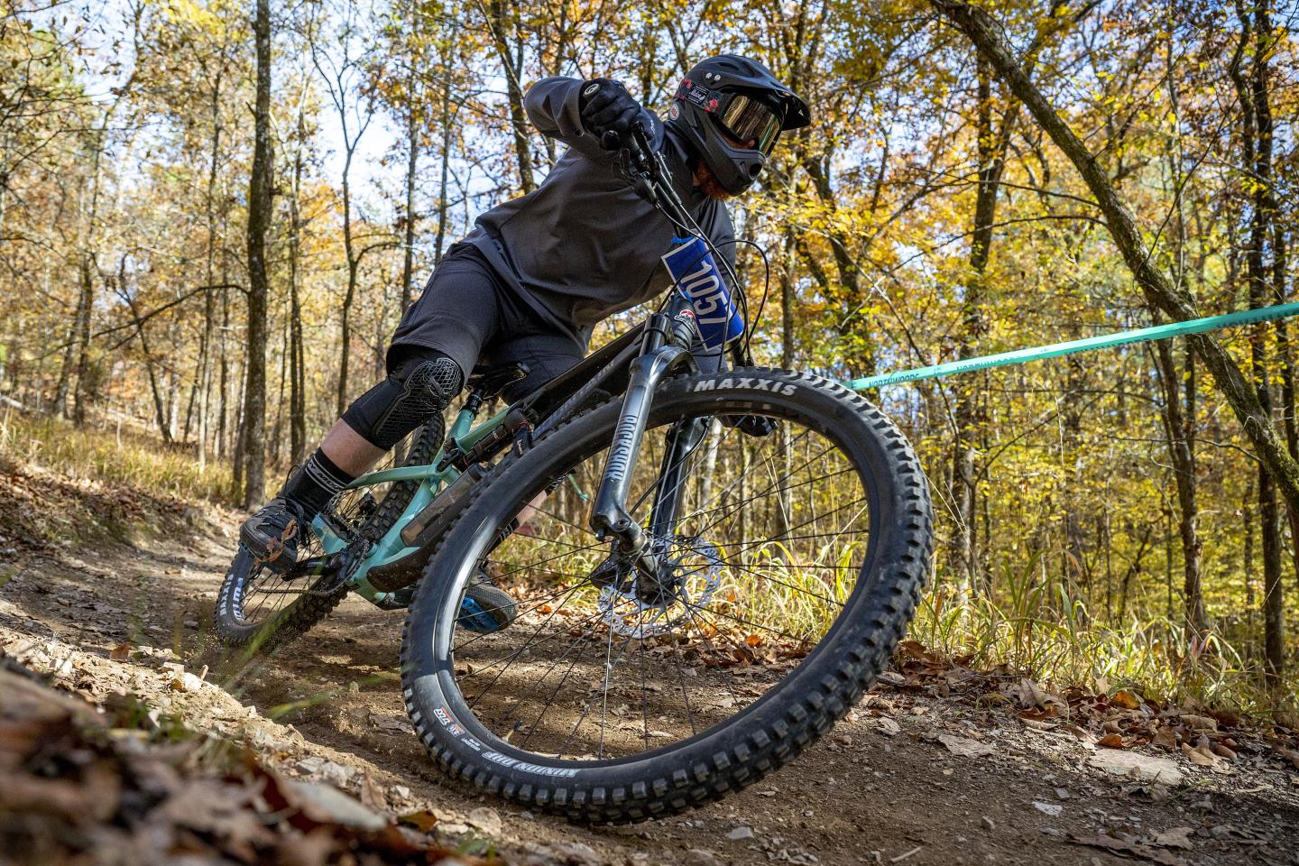 Mountain biker on a forest trail during autumn, leaning into a turn.