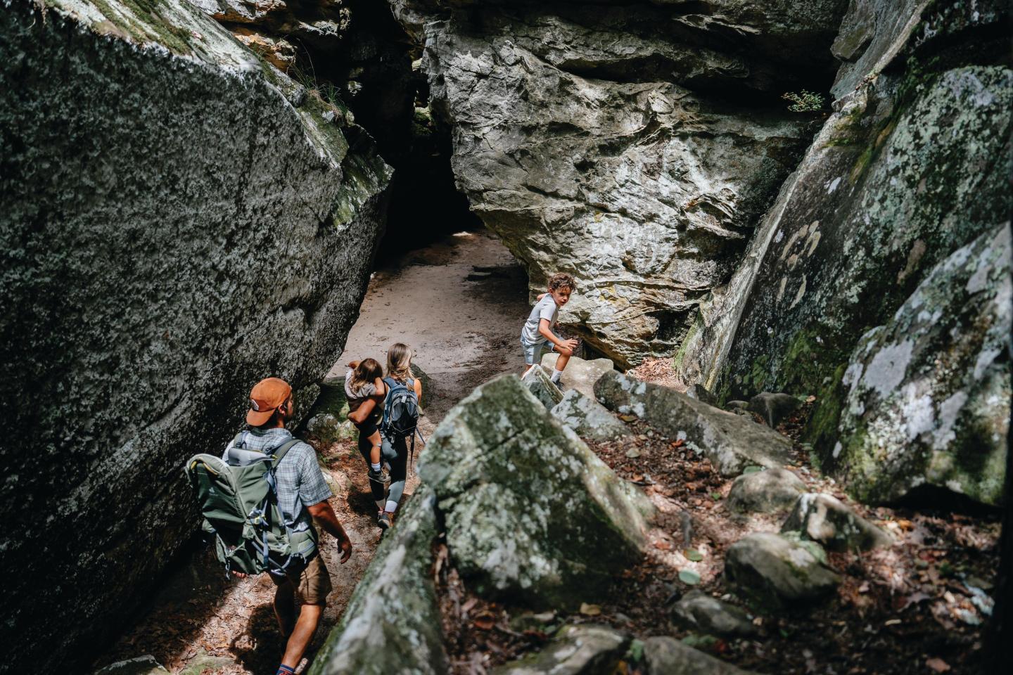 Hikers walk through a rocky, narrow canyon trail.