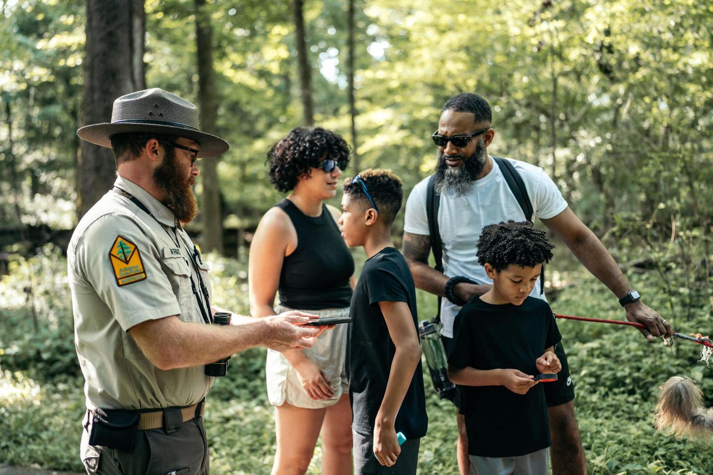 Park ranger talking with a family in a forest setting.