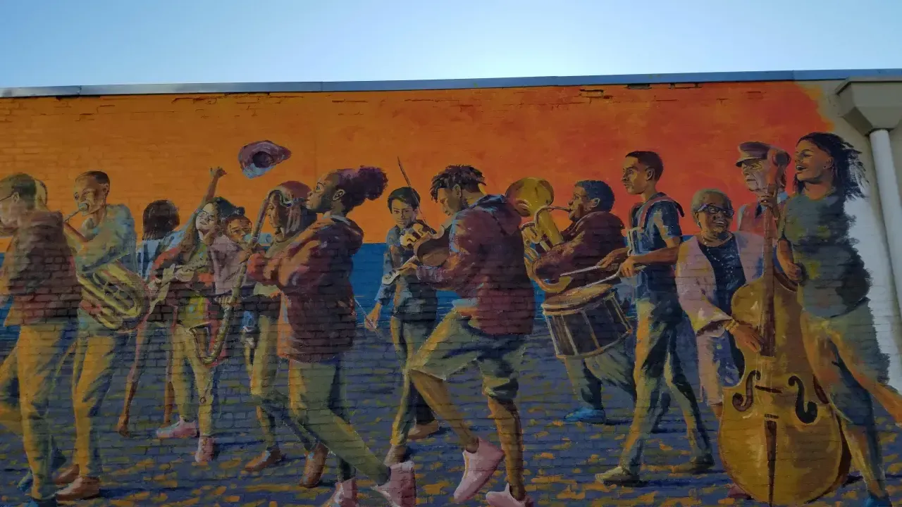 Mural of a lively band playing instruments against an orange sky.