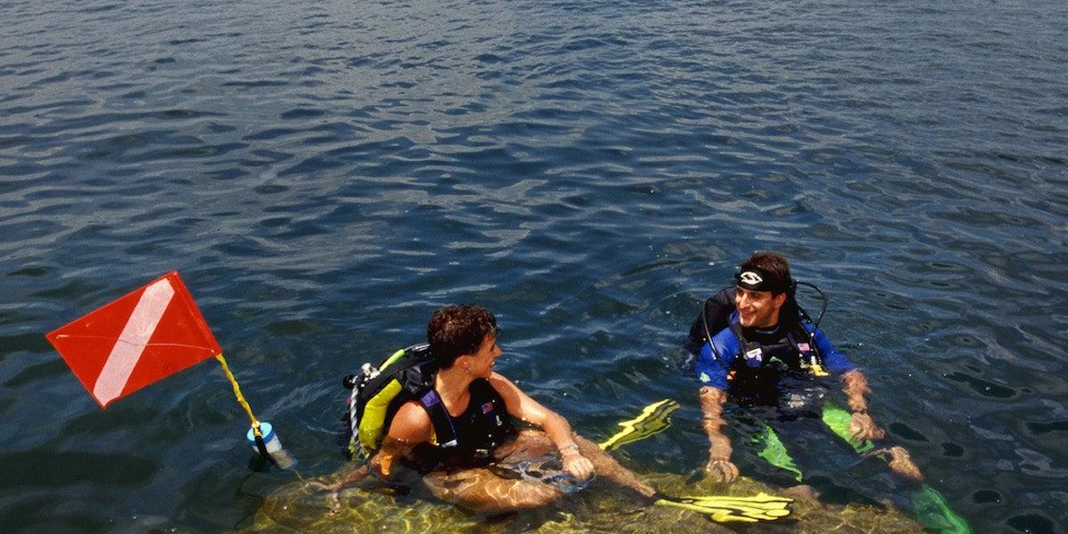 Scuba divers in water, near a red dive flag.