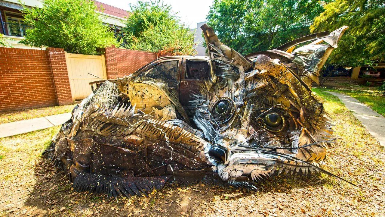 Large cat sculpture made of metal scraps in a park.