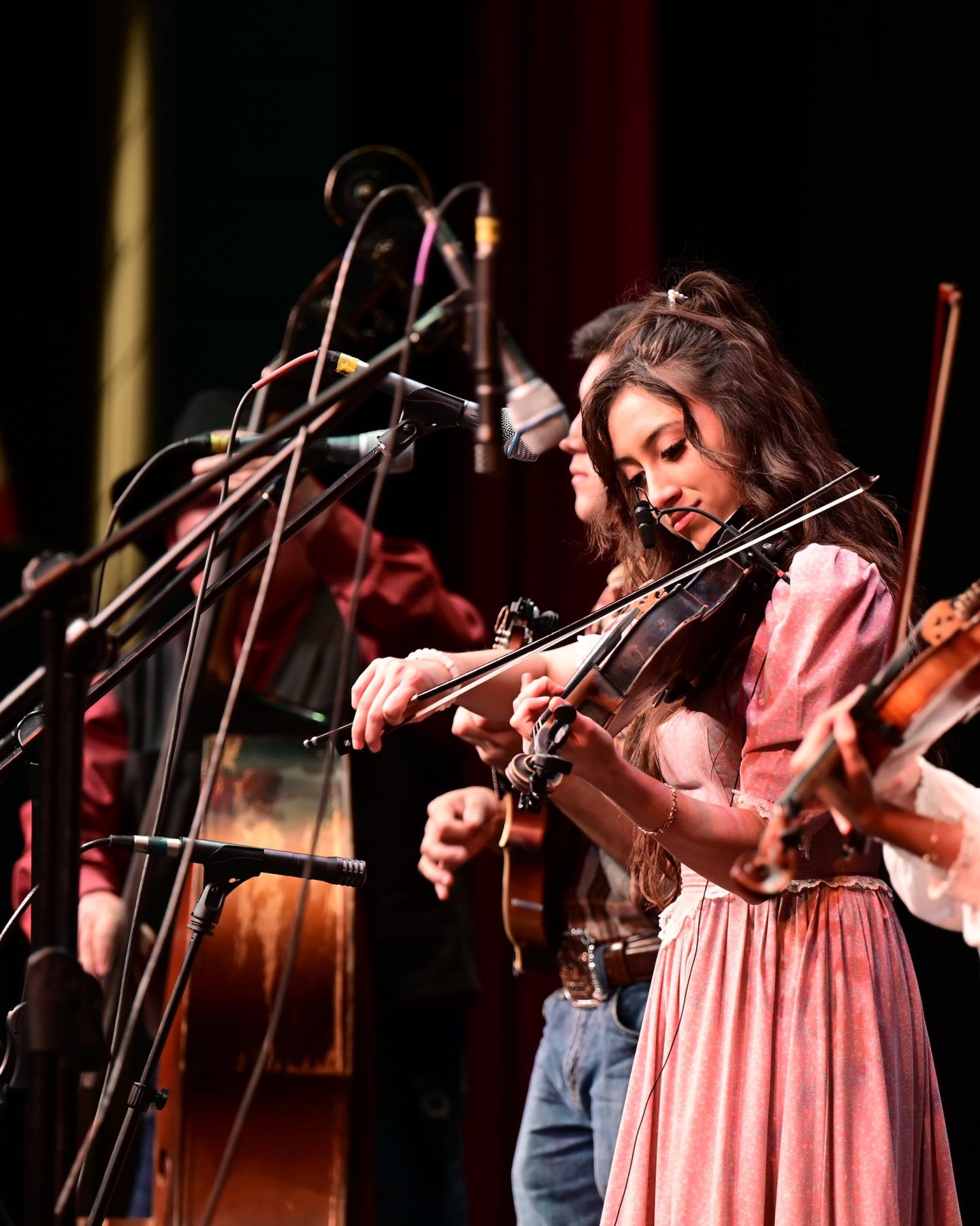Musicians performing on stage with violins, focused and concentrated.