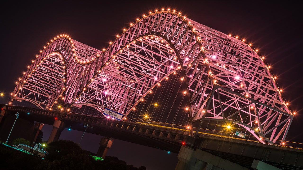 Bridge lit with pink lights against a night sky.