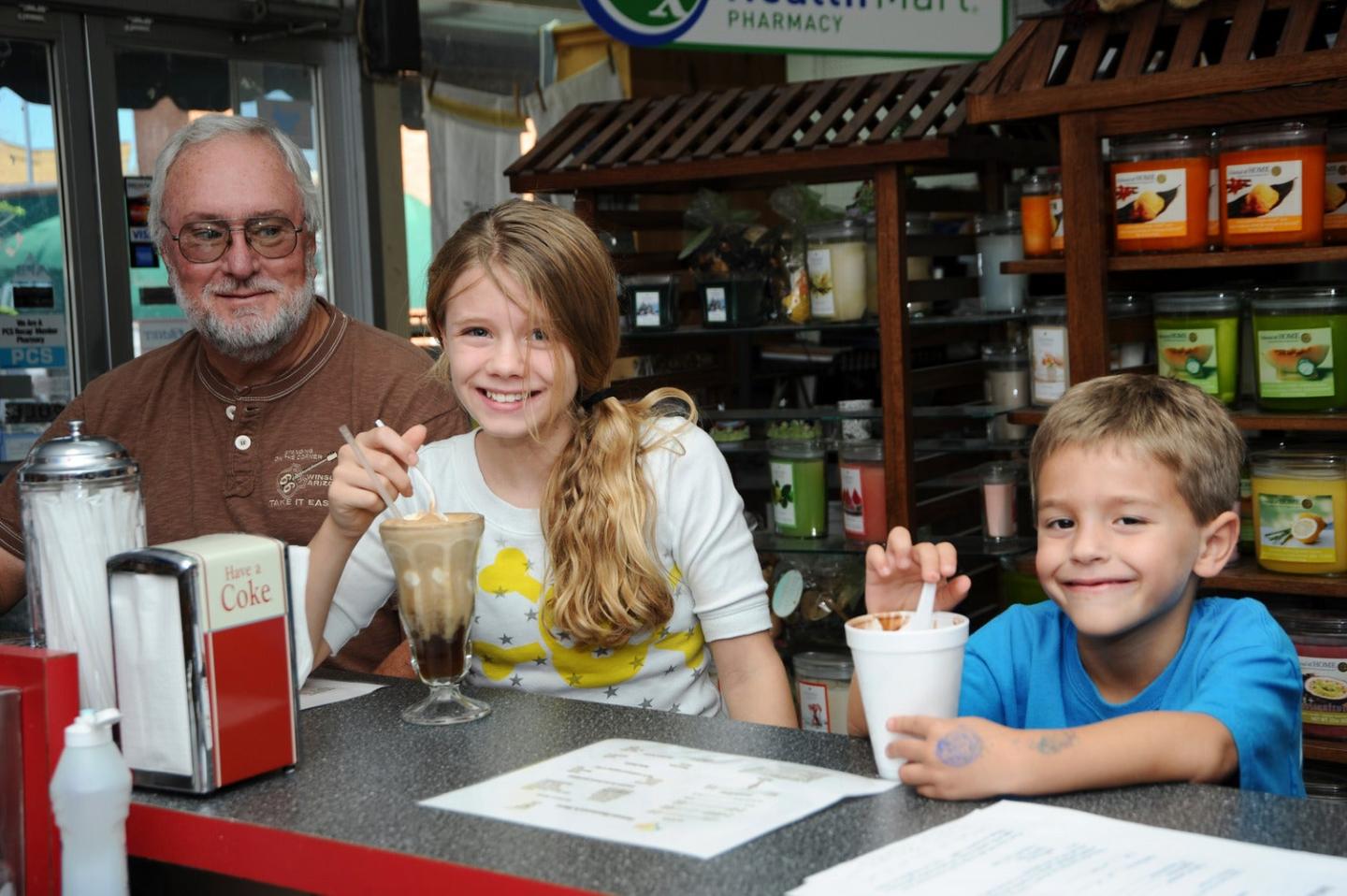 Family enjoying milkshakes at a diner counter.