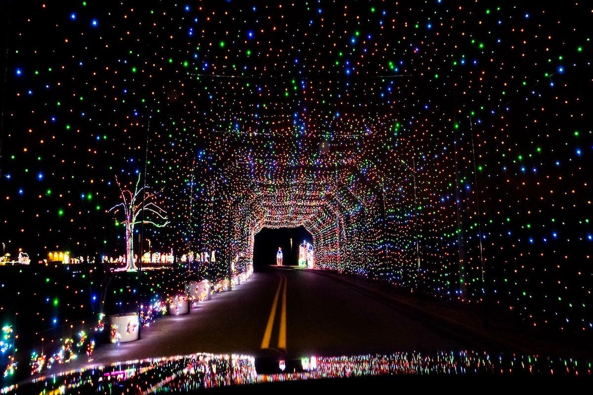 Tunnel illuminated by colorful holiday lights at night.