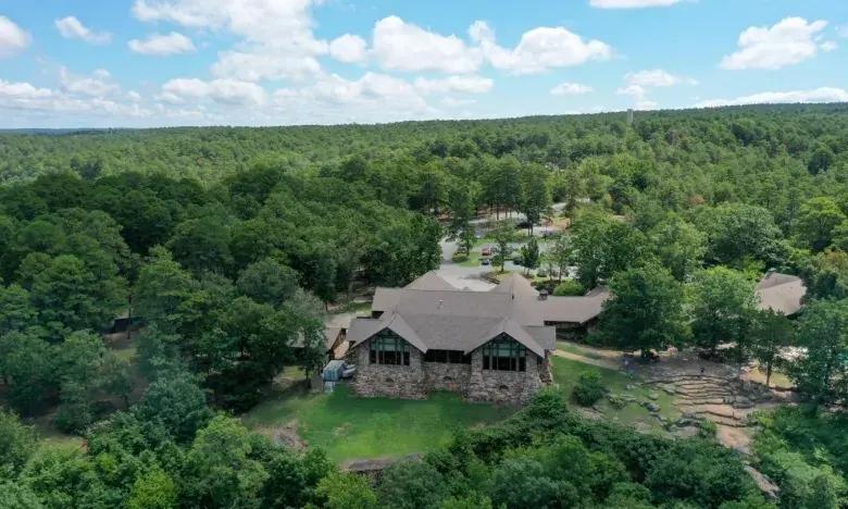 Large house in a lush forest with a clear blue sky.