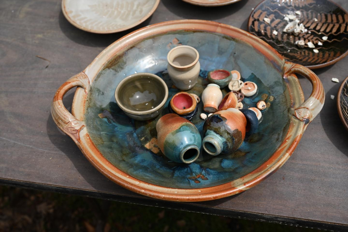 Ceramic bowls and vases in a large decorative dish.