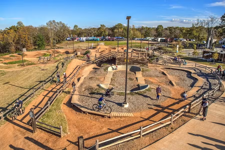Bike park with dirt paths and cyclists under a clear blue sky.