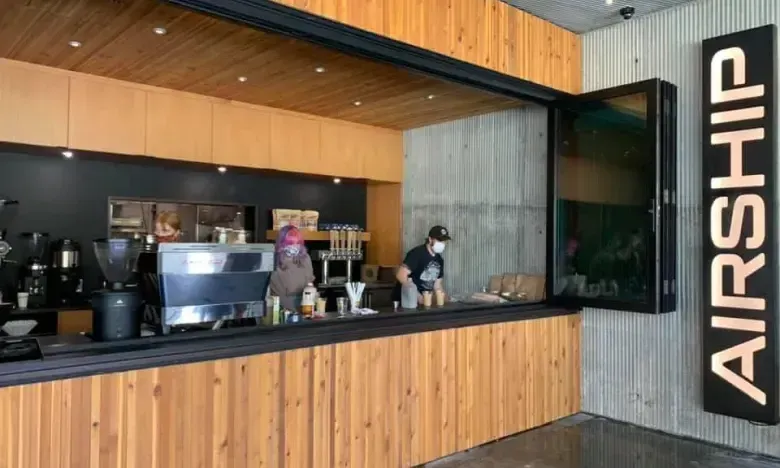 Coffee shop counter with staff behind, sign reads "Airship."