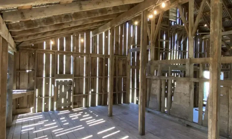 Rustic wooden barn interior with string lights on the ceiling.