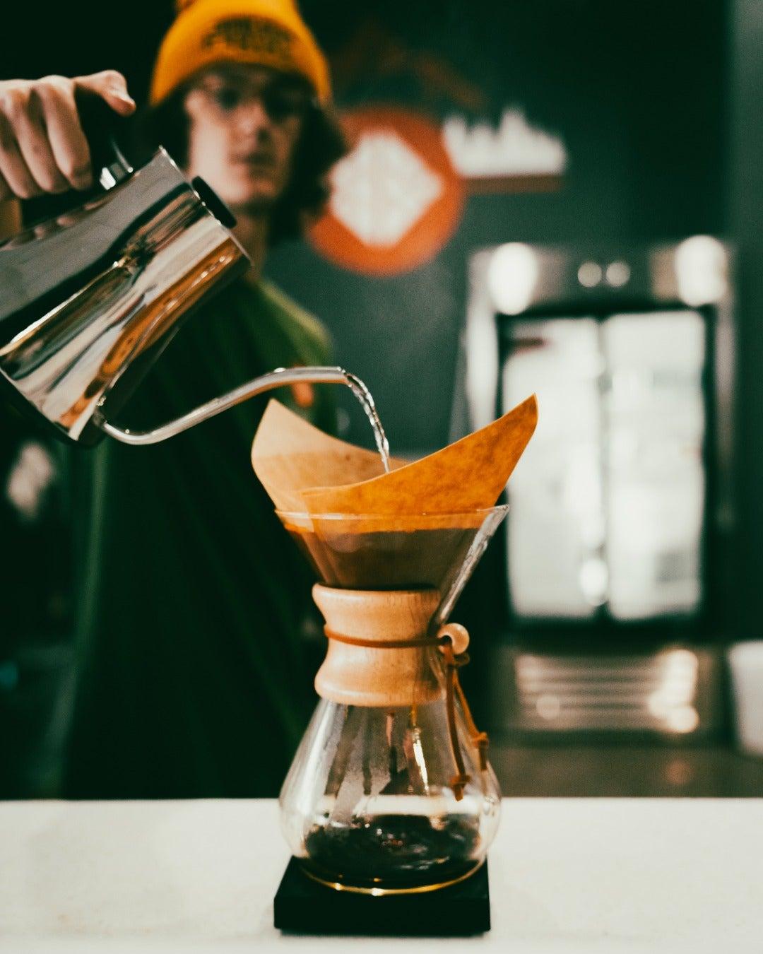 Barista pouring water into a Chemex coffee maker.