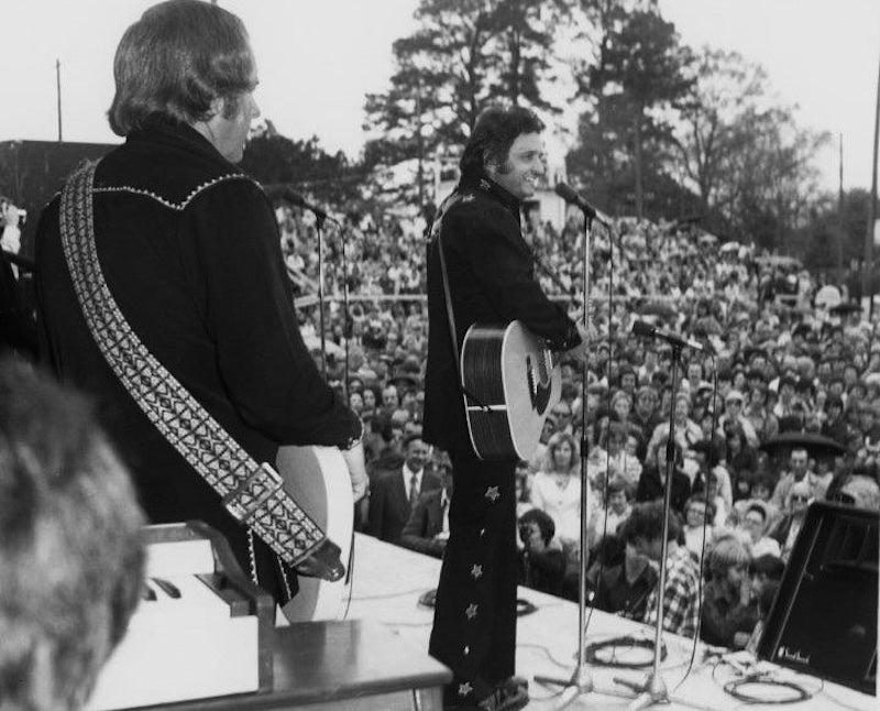 Black and white photo of a musician performing to a large outdoor crowd.
