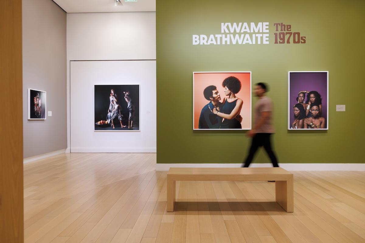 Art gallery with colorful portraits on the walls and a wooden bench in the center.