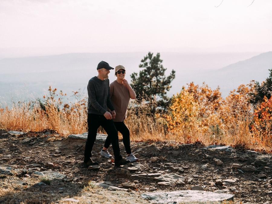 A couple walking on a rocky path, surrounded by autumn foliage.