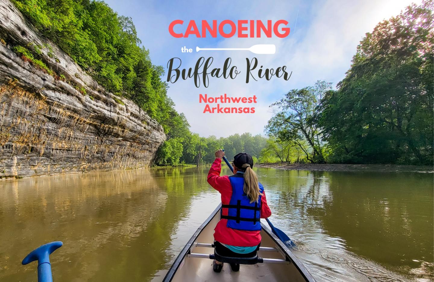 Canoeing on a calm river surrounded by lush greenery and rocky cliffs.