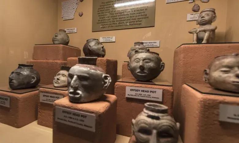 Clay sculptures of heads on display in a museum exhibit.
