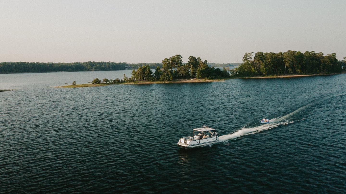 Boat cruising on a lake near a small tree-lined island.