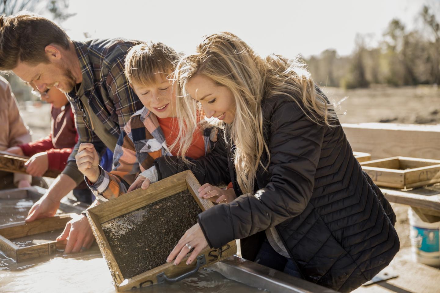 Family panning for gold in a sunny outdoor setting.