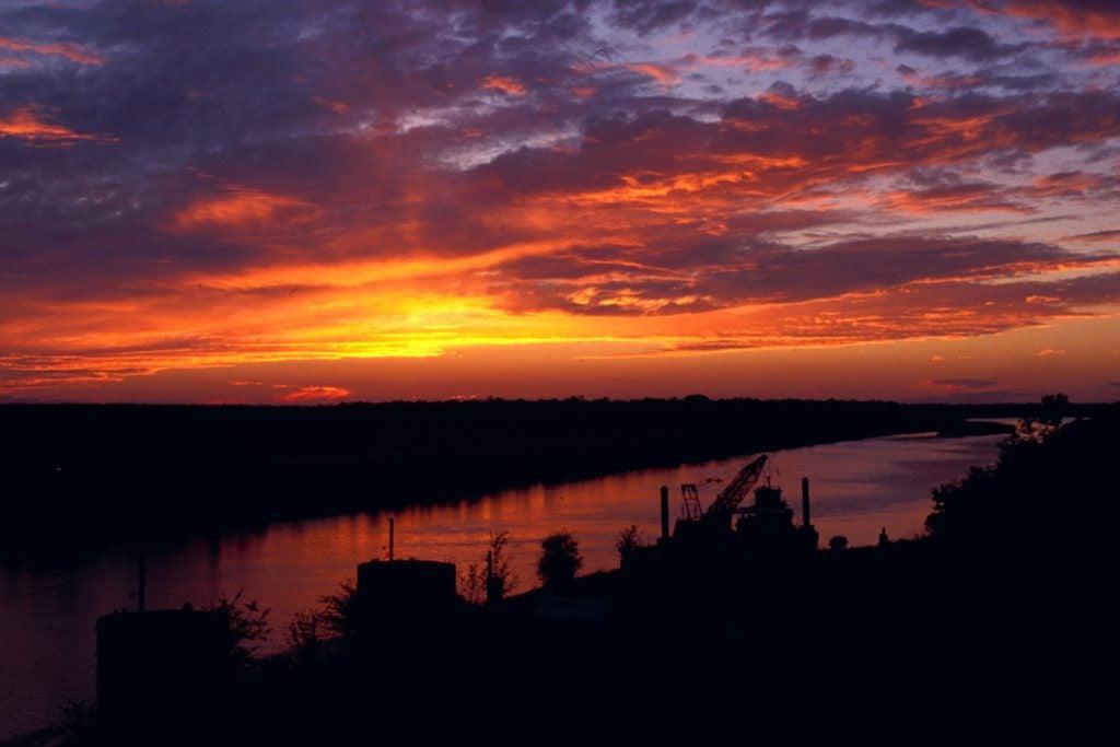 Sunset over a river, with vibrant orange and purple clouds in the sky.