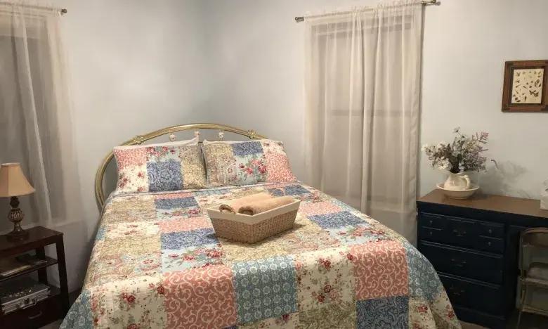 Cozy bedroom with a patchwork quilt on the bed and light curtains.