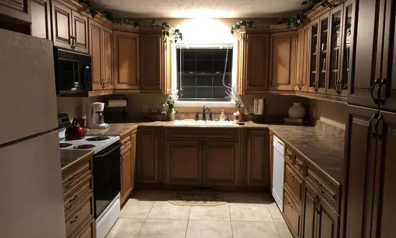 Dimly lit kitchen with wooden cabinets and central window.