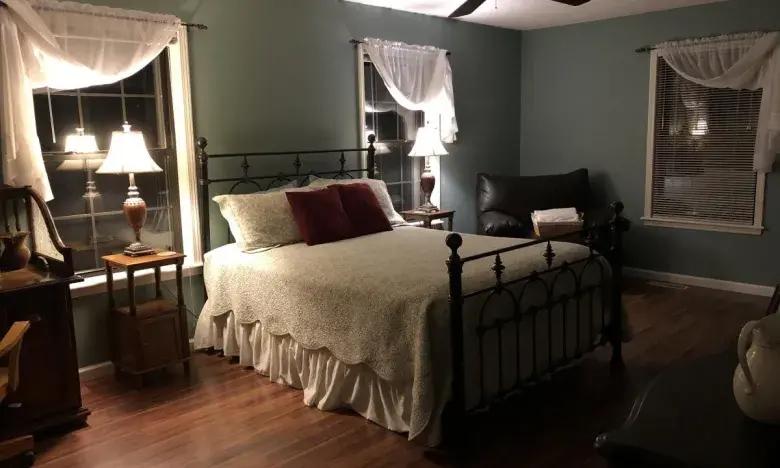 Cozy bedroom with a metal bed, soft lighting, and wooden floor.