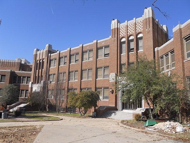 Brick building with large windows under a clear blue sky.