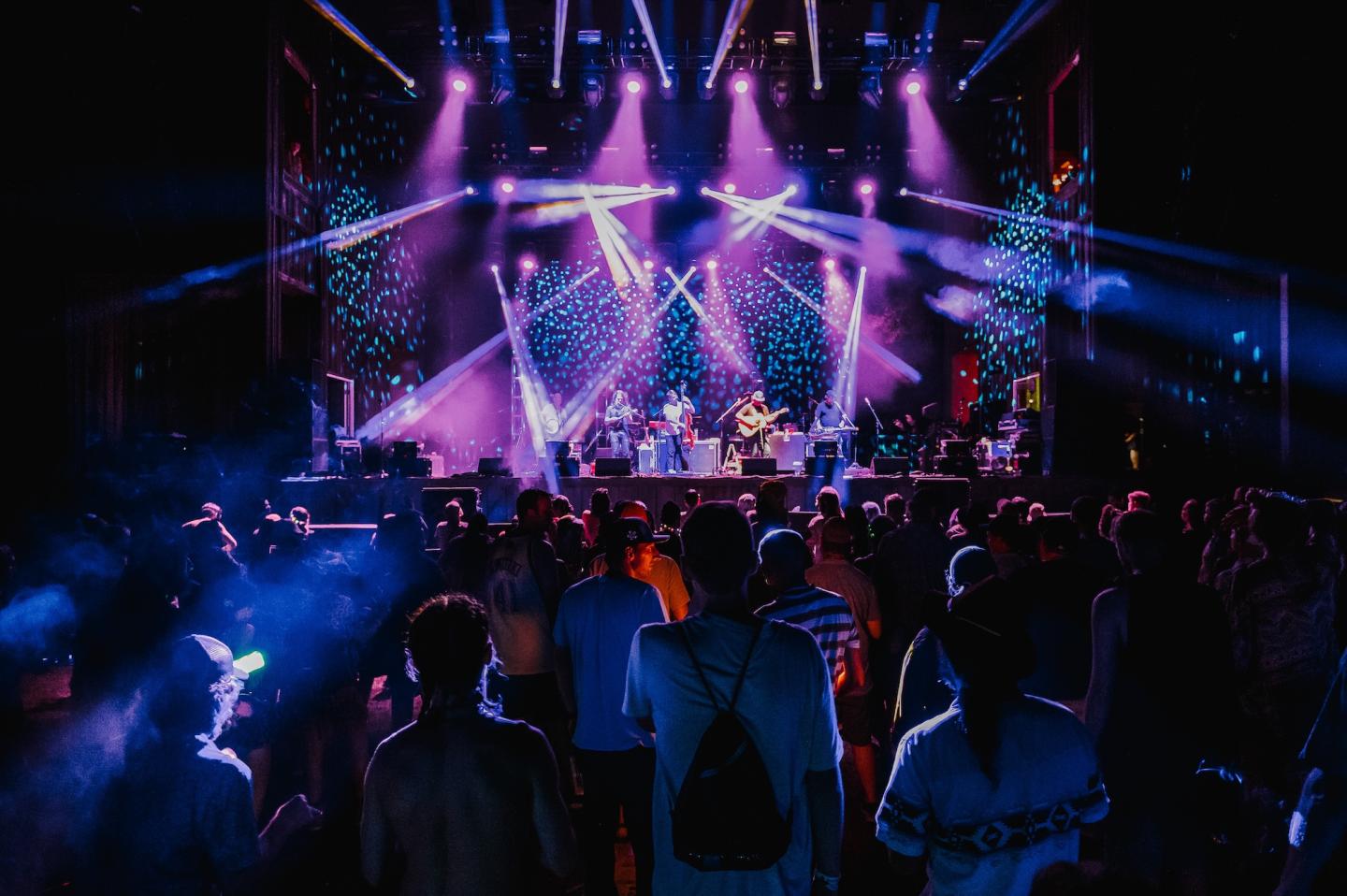 Concert stage with colorful lights and crowd watching.
